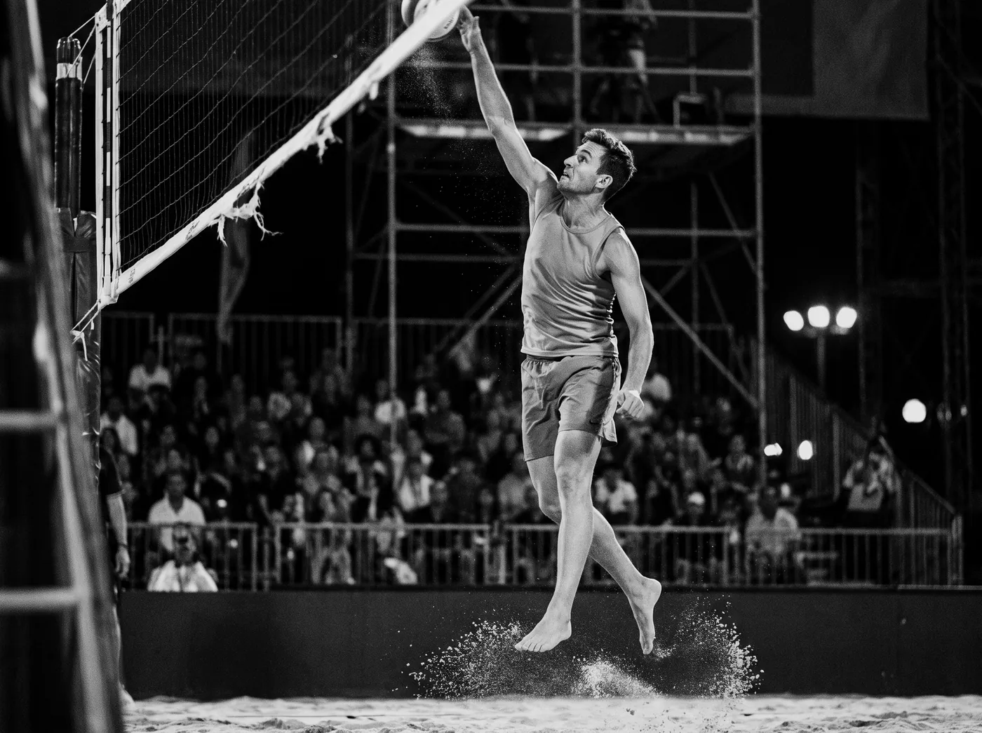 Beach volleyball player spiking above the net at an international tournament
